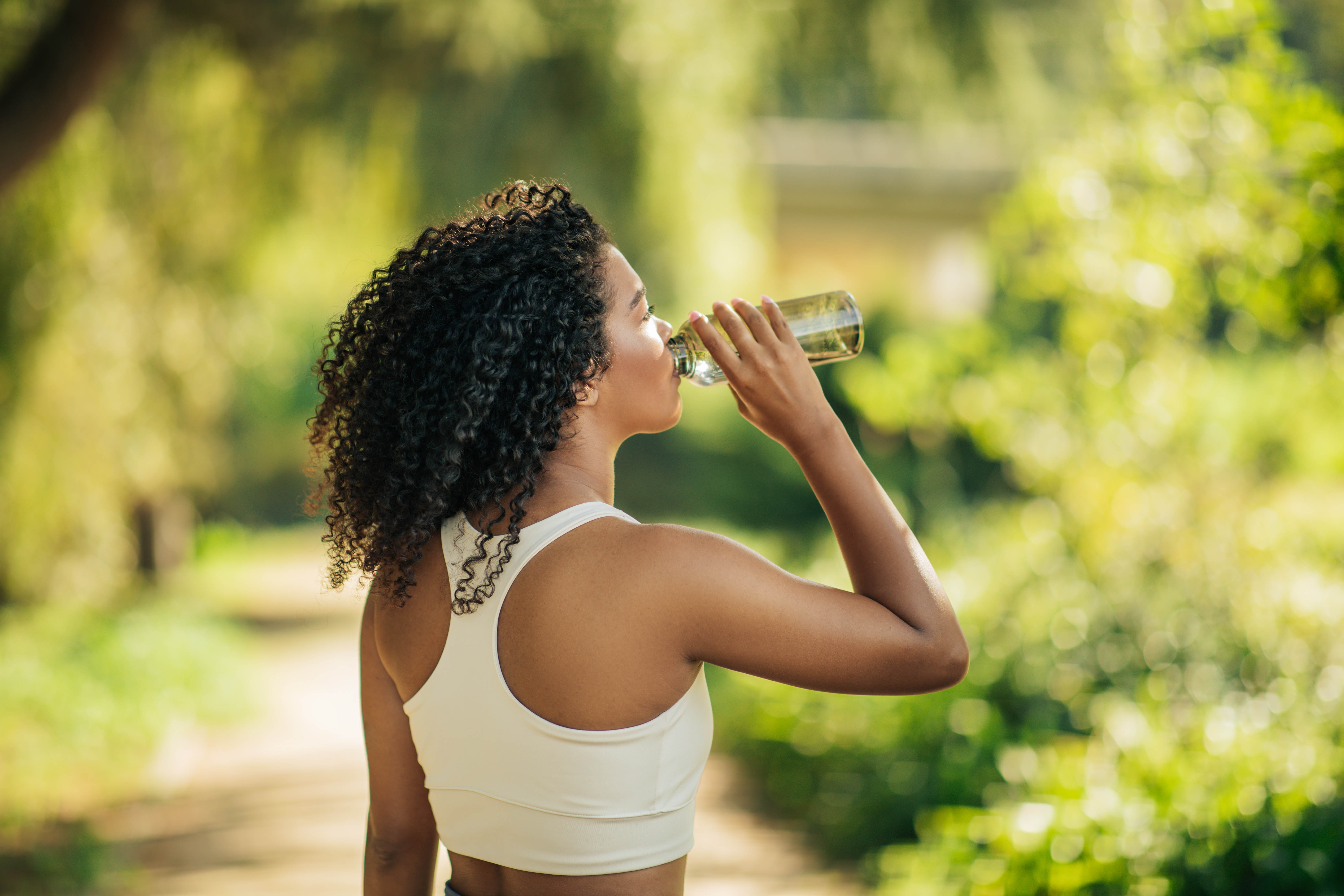 Young woman outside drinking from her glass water bottle